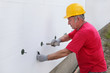 © sima - Construction site styrofoam insulation worker, expansion anchor