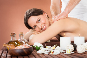 Woman Receiving Back Massaging In Spa