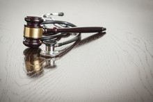 Gavel And Stethoscope On Reflective Table