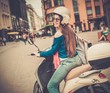 © Nejron Photo - Young cheerful girl driving scooter in in european city