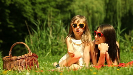 Wall Mural - Picnic. Mother with daughter relaxing on the meadow.