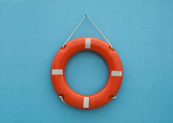 Red life buoy hanging on blue wall. Help and support concept.