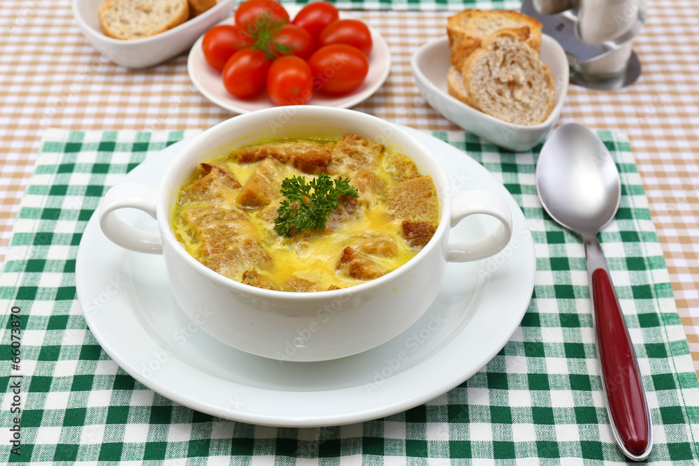 Tasty soup in saucepan on tablecloth, close up