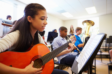 Wall Mural - Female Pupil Playing Guitar In High School Orchestra