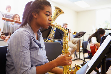 Wall Mural - female pupil playing saxophone in high school orchestra