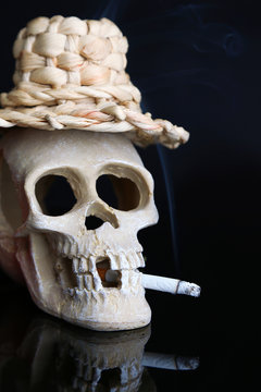 Skull in wicker hat with cigarette isolated on black