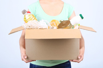 Wall Mural - Volunteer with donation box with foodstuffs on grey background