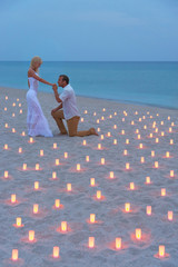 Fototapete - proposal at sea beach in candles against sunset