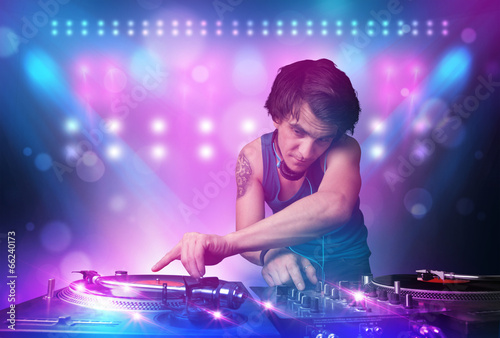 Board z aluminiowym obramowaniem Disc jockey miksująca muzykę na gramofonach na scenie ze światłami i