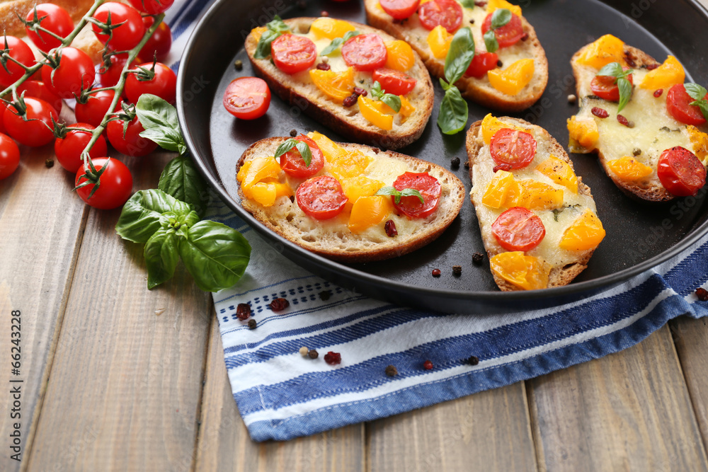 Tasty bruschetta with tomatoes on pan, on old wooden table