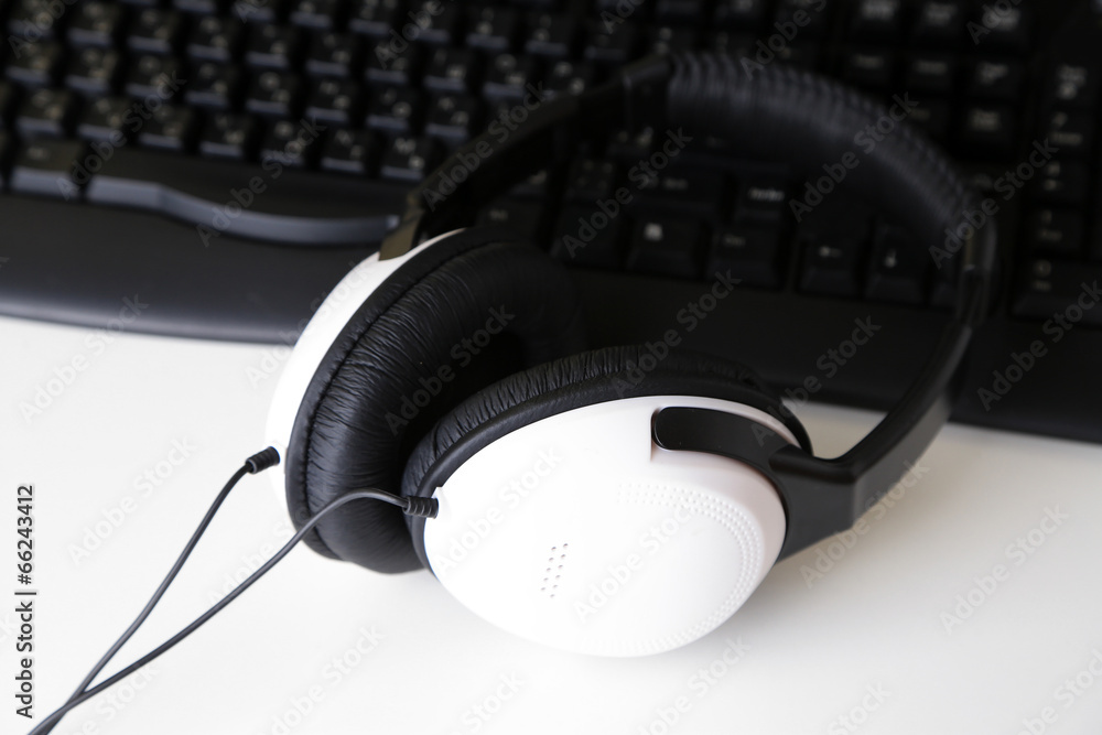 Headphone and keyboard close-up on white desk background