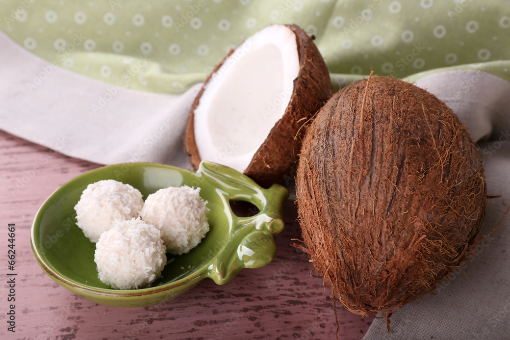 Broken coconut with candies on wooden background