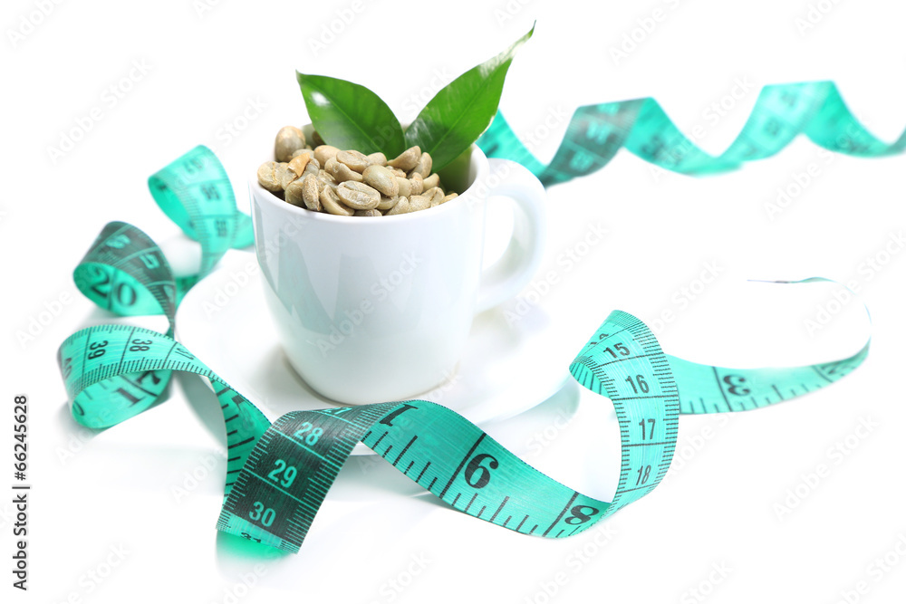 Raw green coffee beans in cup and measuring tape, isolated
