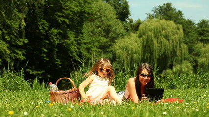 Wall Mural - Child running up to mother with tablet kissing her on the meadow