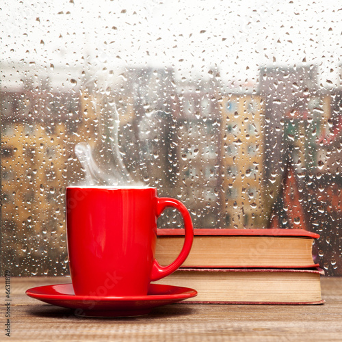 Naklejka nad blat kuchenny Steaming coffee cup on a rainy day window background
