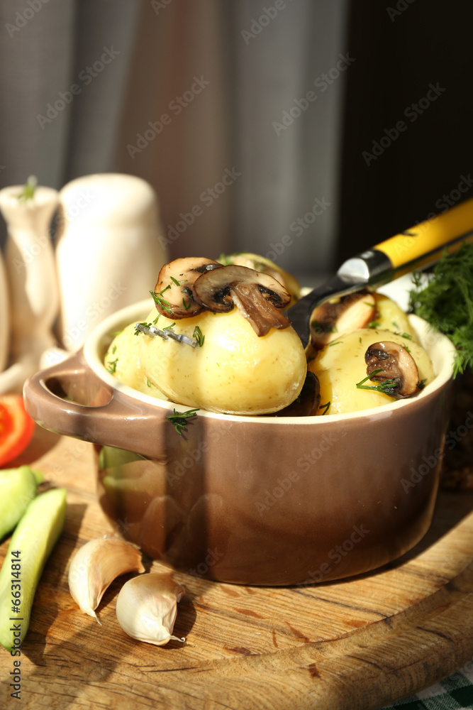 Young boiled potatoes in pan with vegetables on table in