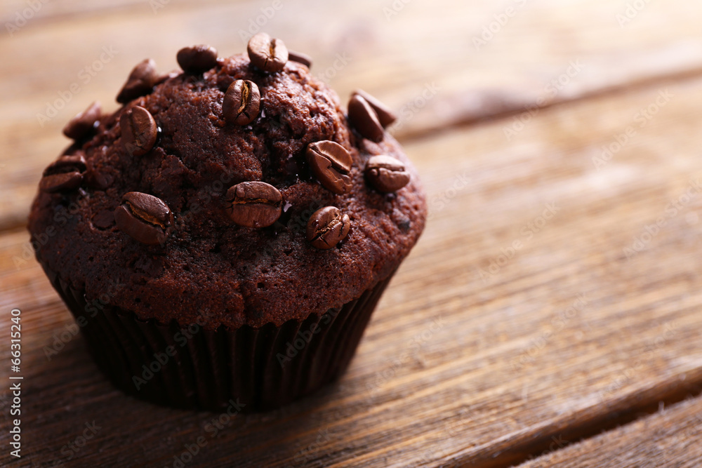 Chocolate muffin and coffee grains on wooden background
