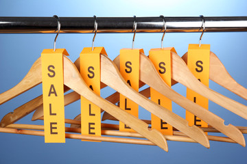 wooden clothes hangers as sale symbol on blue background.