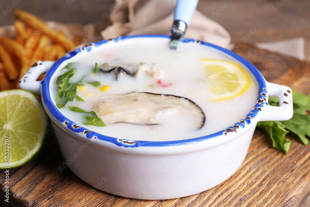 Tasty soup with oysters on wooden table