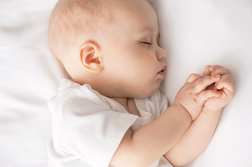 Wall Mural - Carefree sleep little baby with a soft toy on the bed