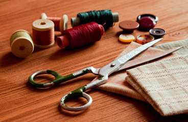 Close-up sewing tools on wooden background, vintage style