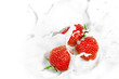 Red strawberry fruits falling into the milky splash