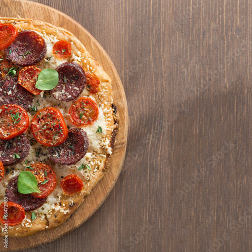 Naklejka samoprzylepna Włoska pizza z salami i pomidorami na drewnianym stole