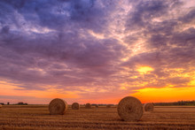 Sunset Over Farm Field With Hay Bales