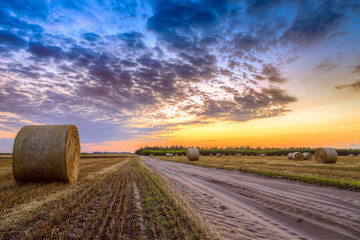 Wall Mural - Sunset over rural road and hay bales