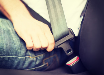 man fastening seat belt in car