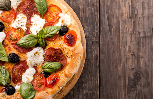 Fototapeta do kuchni Rustic pizza with salami, mozzarella, olives and basil on wooden