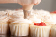Gourmet strawberry filled cupcakes with white chocolate frosting - being piped by a chef