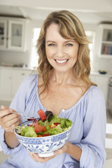 Wall Mural - Mid age woman eating salad