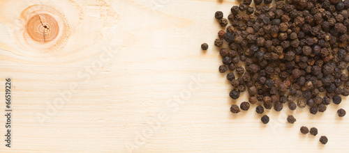Fototapeta na wymiar black pepper on wooden background - top view