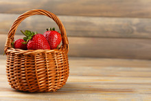 Red Ripe Strawberries In Wicker Basket On Wooden Background