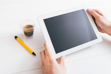 Hands of a man holding blank tablet device over wooden table