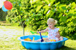 Happy little girl playing in sandbox in the garden