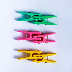 green, yellow and pink clothes peg isolated on a white backgroun