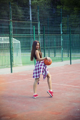 Wall Mural - Beautiful young woman playing basketball outdoors