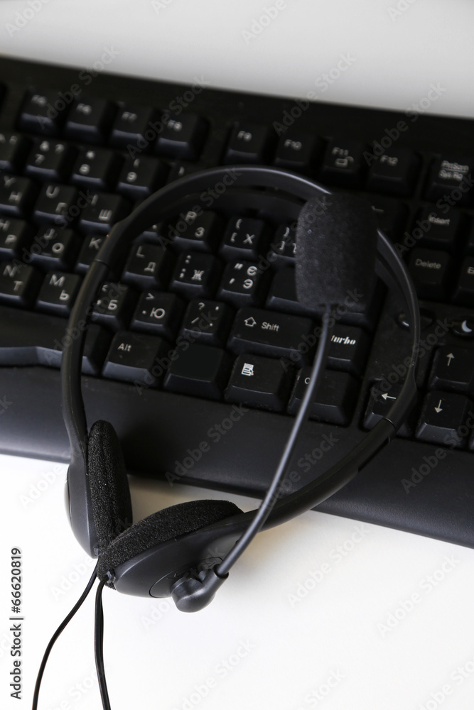 Headphone and keyboard close-up on white desk background