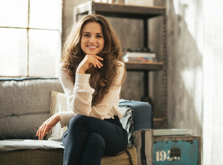 Happy young woman sitting in loft apartment