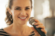 © Alliance - Portrait of happy young woman singing with microphone