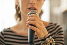 Closeup On Young Woman Singing With Microphone