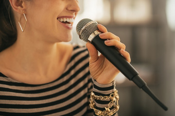 Wall Mural - Closeup on happy young woman singing with microphone