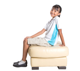 Young Asian school girl in uniform sitting on a couch