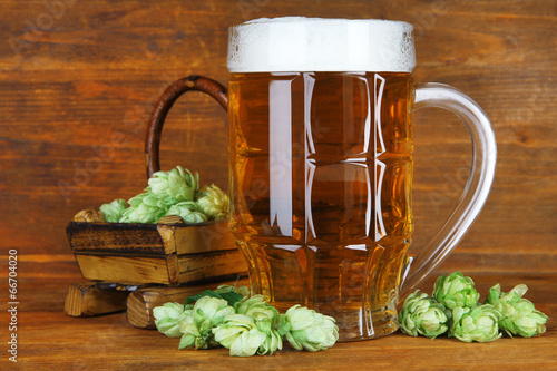 Naklejka na szybę Glass of beer and hops, on wooden table