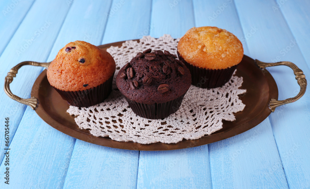 Tasty muffins on tray, on color wooden background