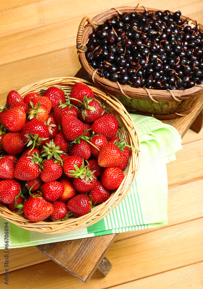 Fresh berries in baskets on wooden background