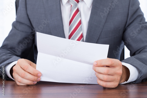 Plakat na papierze fotorealistycznym Biznesmen czytanie dokumentu na biurku