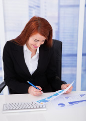 Wall Mural - Businesswoman Analyzing Graph At Desk